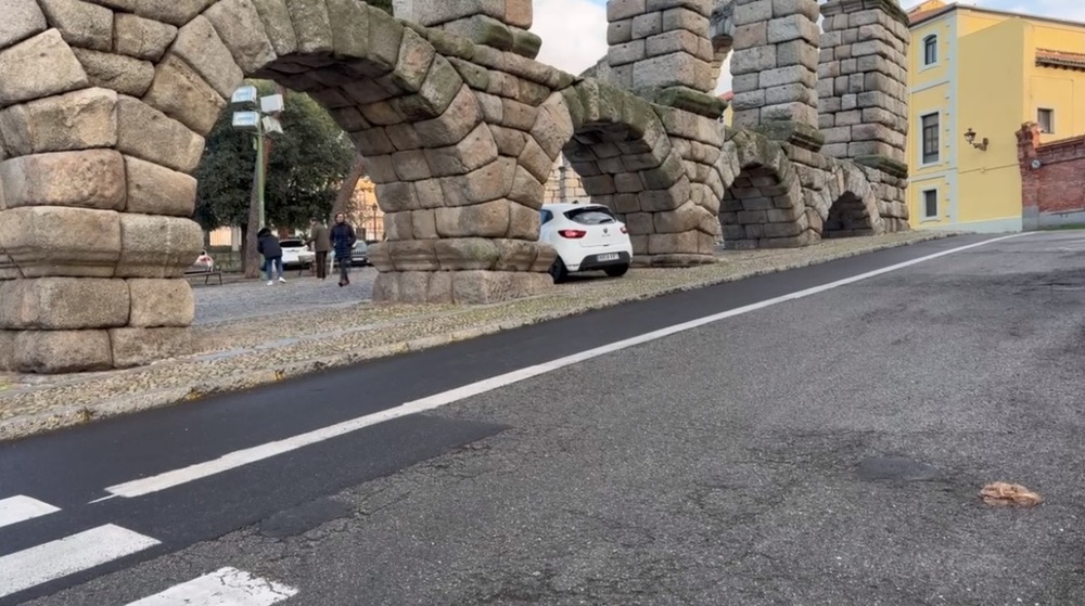 Un coche se sube a la acera para cruzar bajo el Acueducto