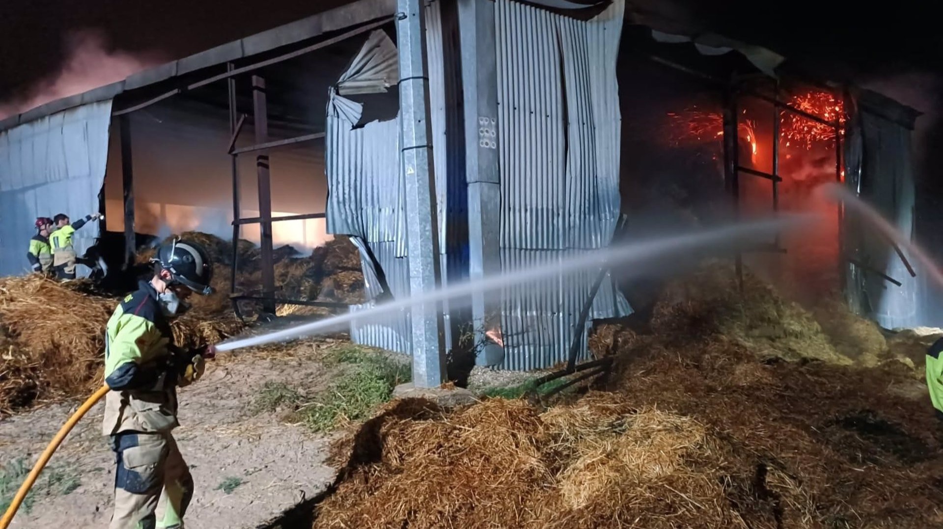 Bomberos trabajan en la extinción del incendio en un almacén de paja en Campos del Río