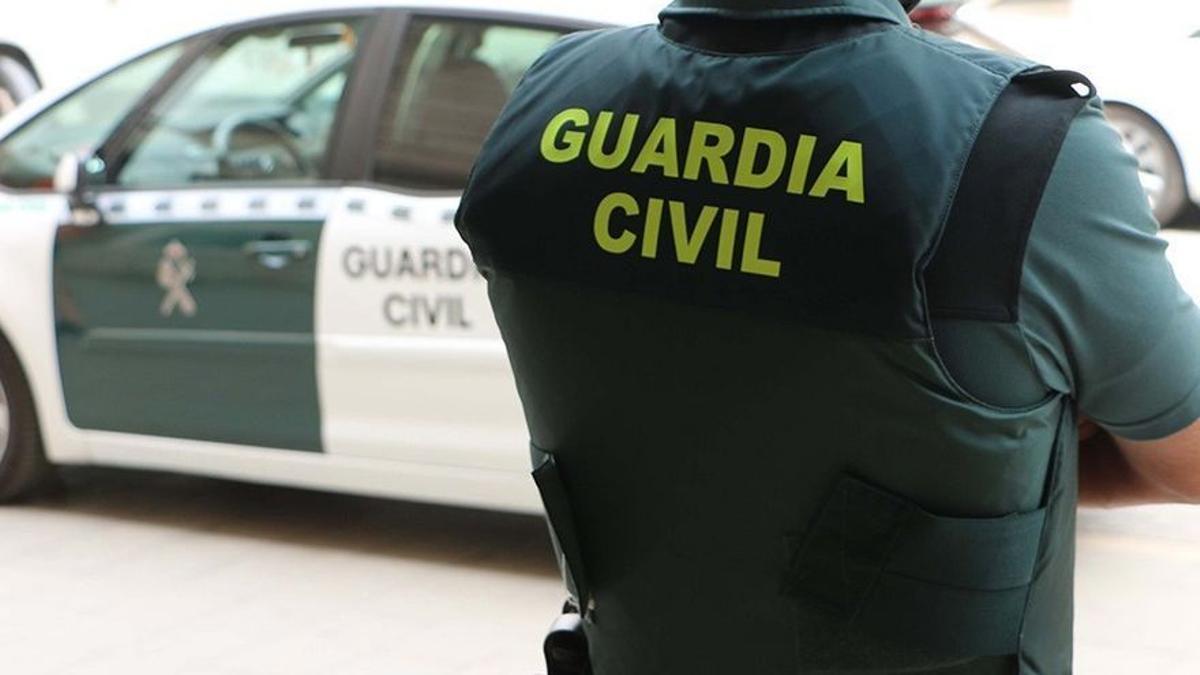 Agente de la Guardia Civil frente a us vehículo.