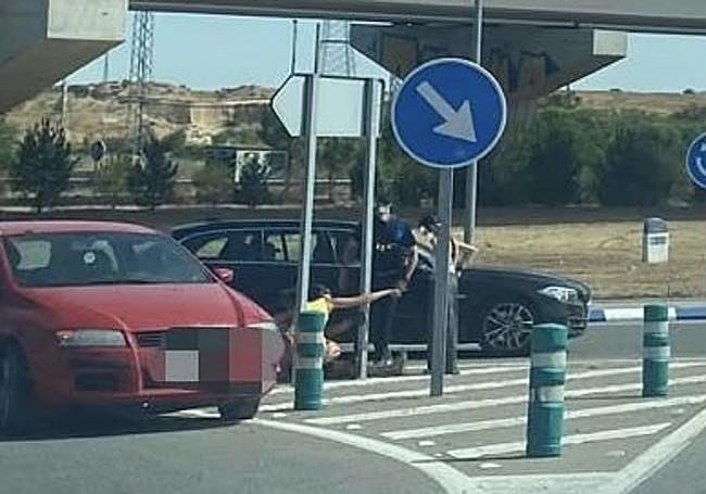 Policía y testigos presenciales auxiliando al ciclista herido, tendido a la izquierda en la calzada.