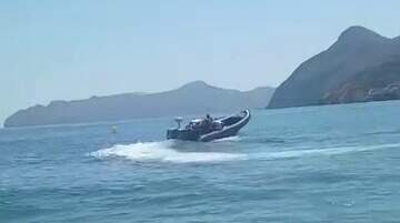 Una lancha recoge bidones de combustible a plena luz del día en la playa de El Portús, en Cartagena